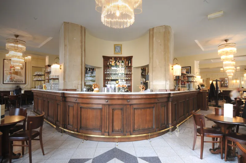 La salle du Café Broglie, le grand comptoir en bois sous les lustres