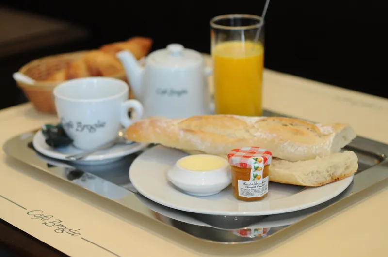 Plateau du petit-déjeuner : café, théière, baguette, croissant et jus d'orange